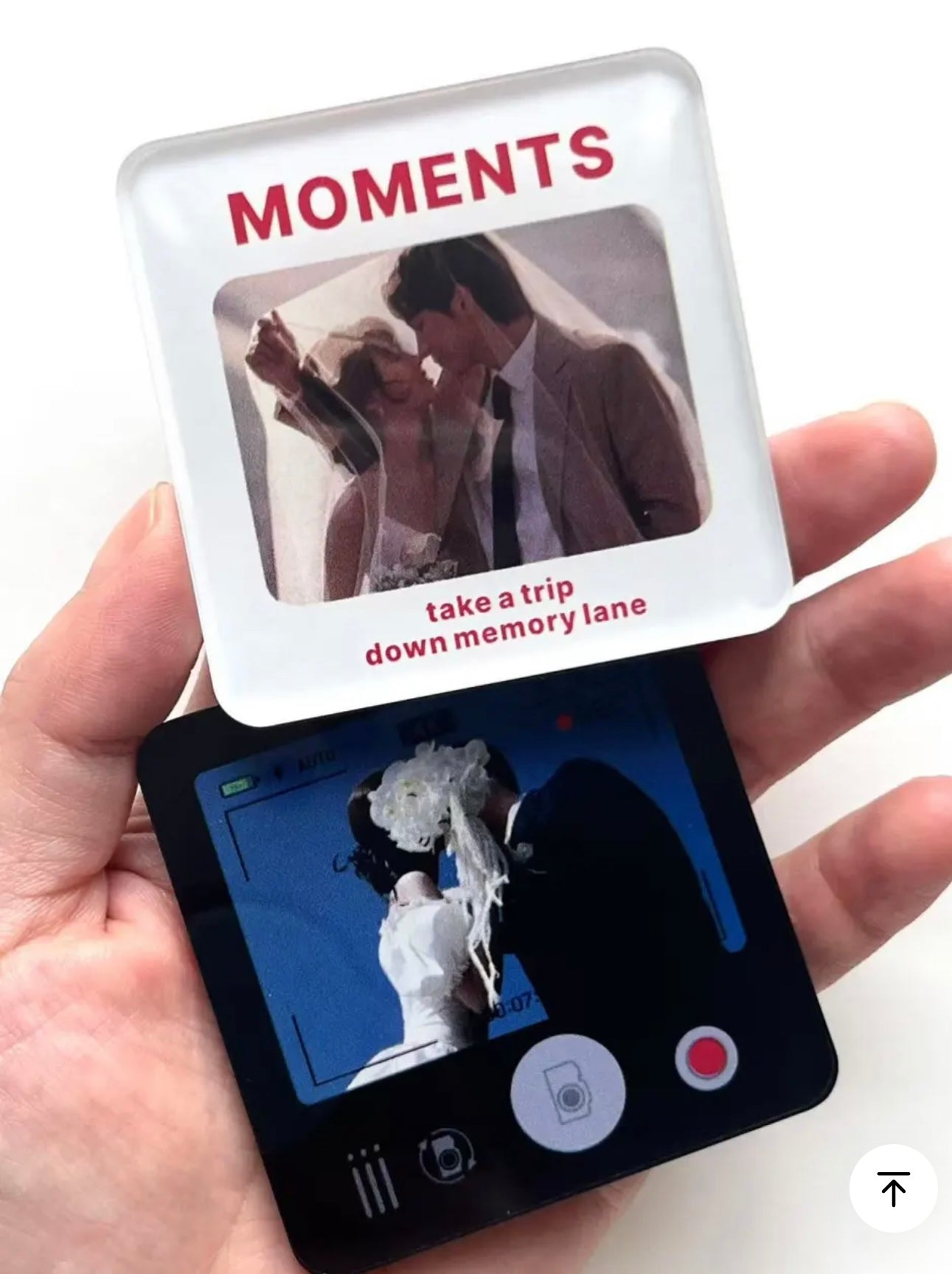 Hand holding a device with a photo album interface showing a couple and text 'Moments'.