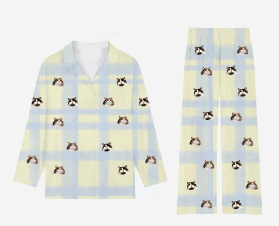A person sitting with a white cat on their lap, wearing custom unisex milk silk pajamas set with pet faces printed on it.