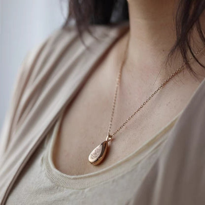 Rose gold necklace with a teardrop pendant worn by a person Memorial Jewelry